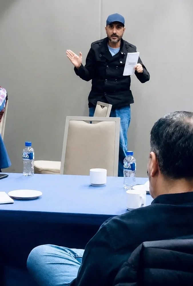 Oscar Onofre de pie frente a un grupo, durante una sesión